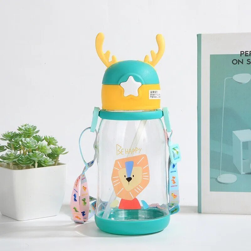 Kids antler sippy cup with deer design styled with a plant and book, a leakproof cup for nursery table settings.