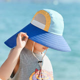 Child wearing a colorful sun hat with a blue brim against a blurred water background