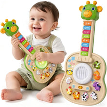 Smiling baby holding a green giraffe toy guitar beside the guitar with farm animal buttons