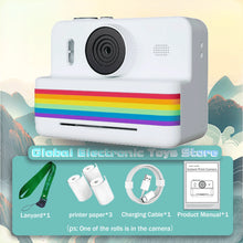 White instant print camera with a green lanyard, three paper rolls, a USB cable and a manual