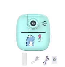 Teal dinosaur kids camera with a paper roll, USB cable, lanyard and manual below it