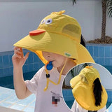 Child wearing a yellow duck-themed sun hat by a pool.