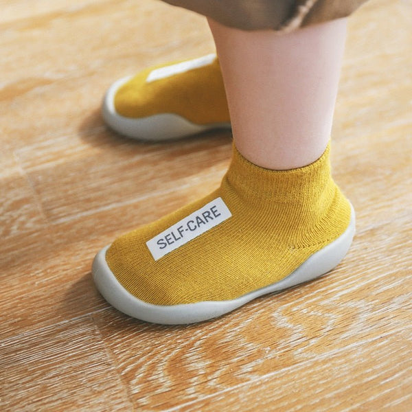 Yellow socks with 'SELF-CARE' label worn by a person 