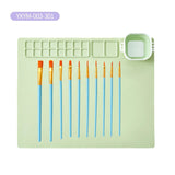 Set of paintbrushes with a green paint palette and container on a white background