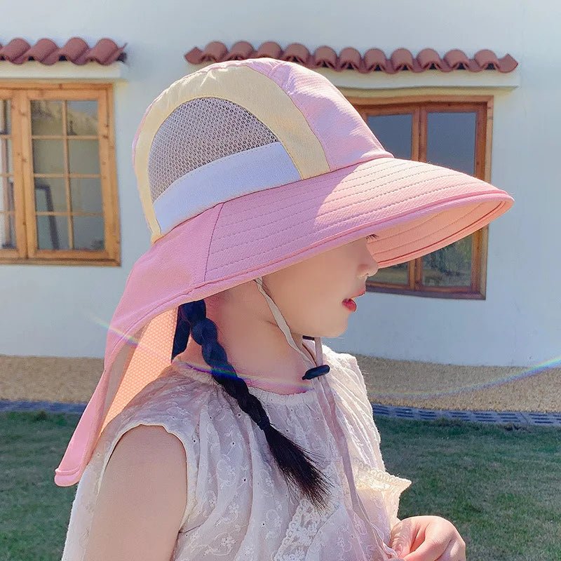 Child wearing a pink sun hat with a building in the background