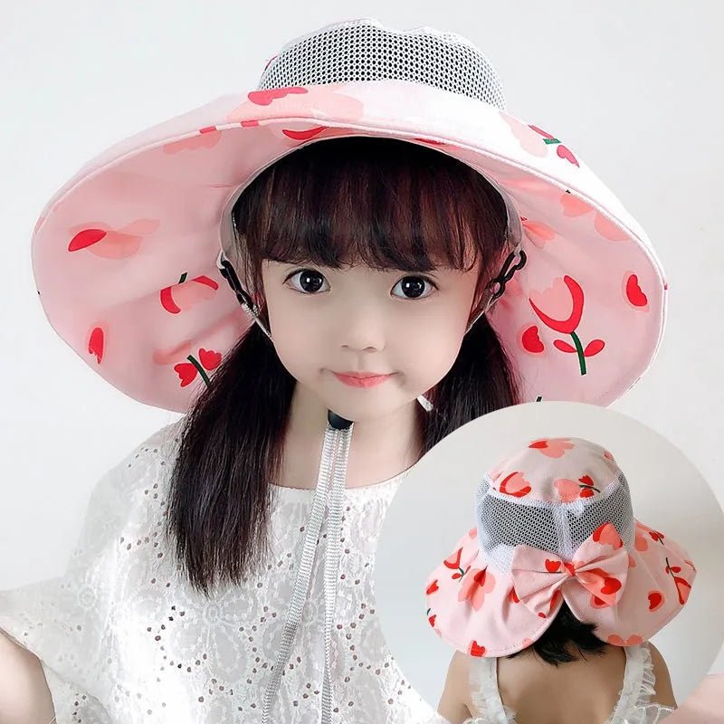 Child wearing a pink floral sun hat with a cherry design.