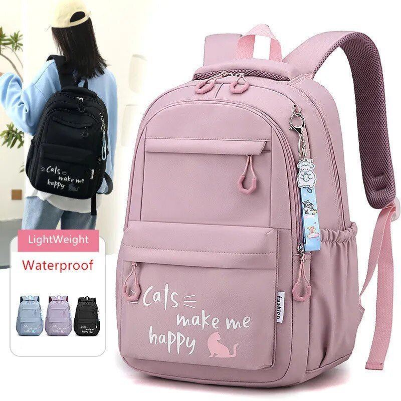 Pink backpack with 'Cats make me happy' text and a charm, shown with a person wearing a black backpack.