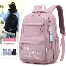 Pink backpack with 'Cats make me happy' text and a charm, shown with a person wearing a black backpack.