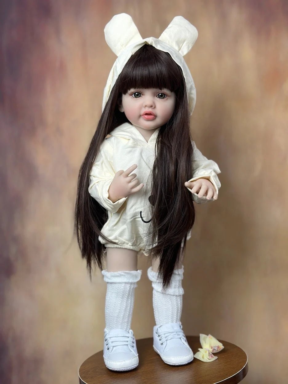 Lifelike Reborn Baby Girl Doll in soft silicone with long hair and a white bunny-ear outfit for nursery display and play.