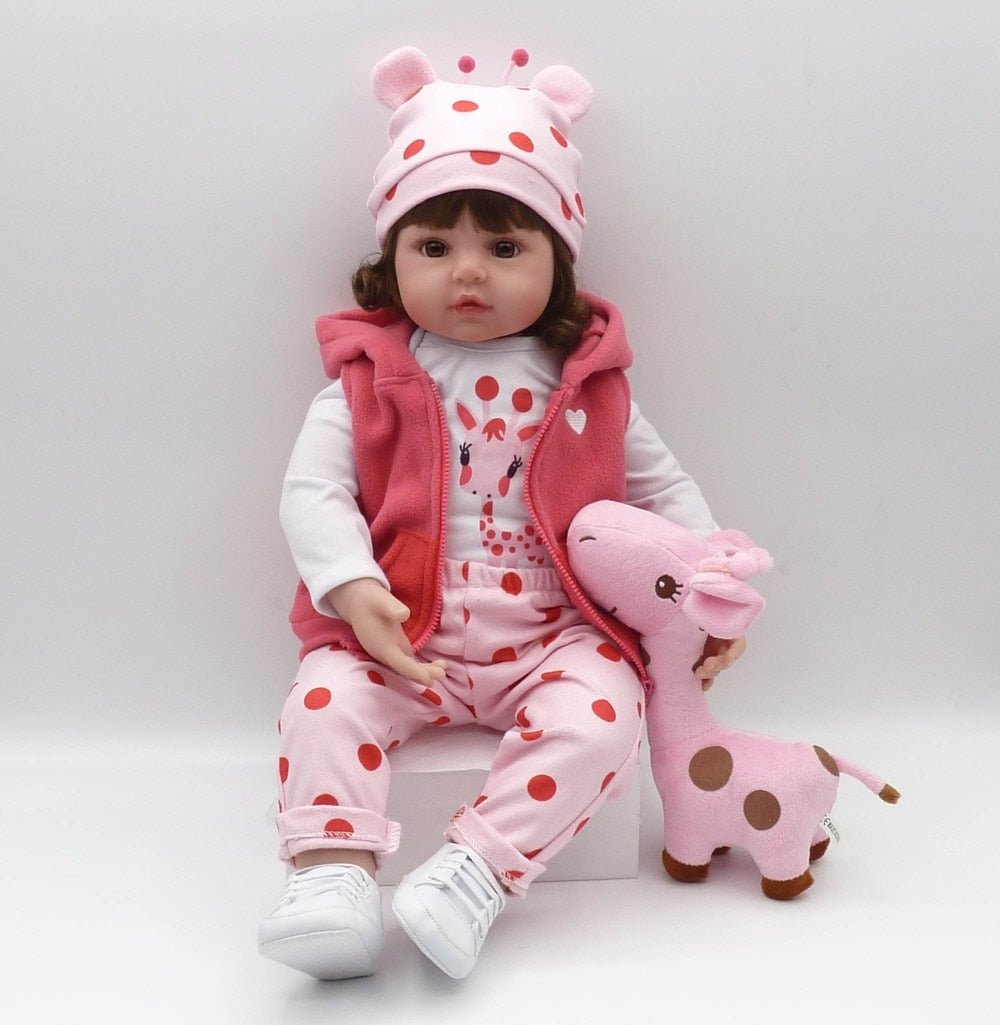 Child's doll in pink outfit with polka dots, holding a pink stuffed giraffe 