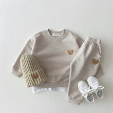 Children's clothing set with a beige sweatshirt, pants, a hat, and shoes.