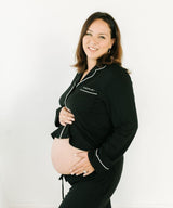 A pregnant woman wearing a black outfit with white piping.