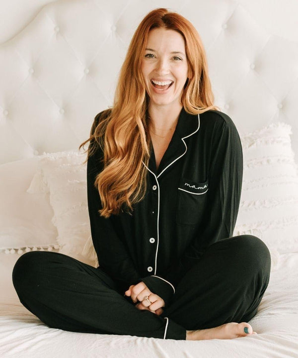 A woman wearing black pajamas with a visible brand logo.