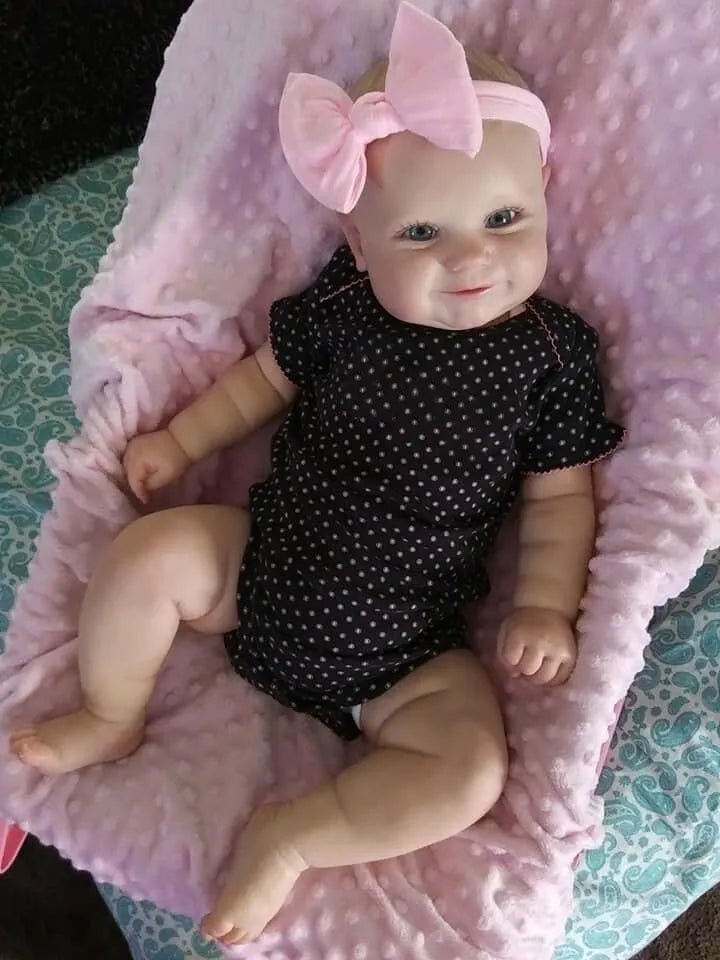 Maddie Reborn Doll, baby doll in a black polka dot outfit with a pink bow on a pink blanket, for nursery display and collectible gifting.