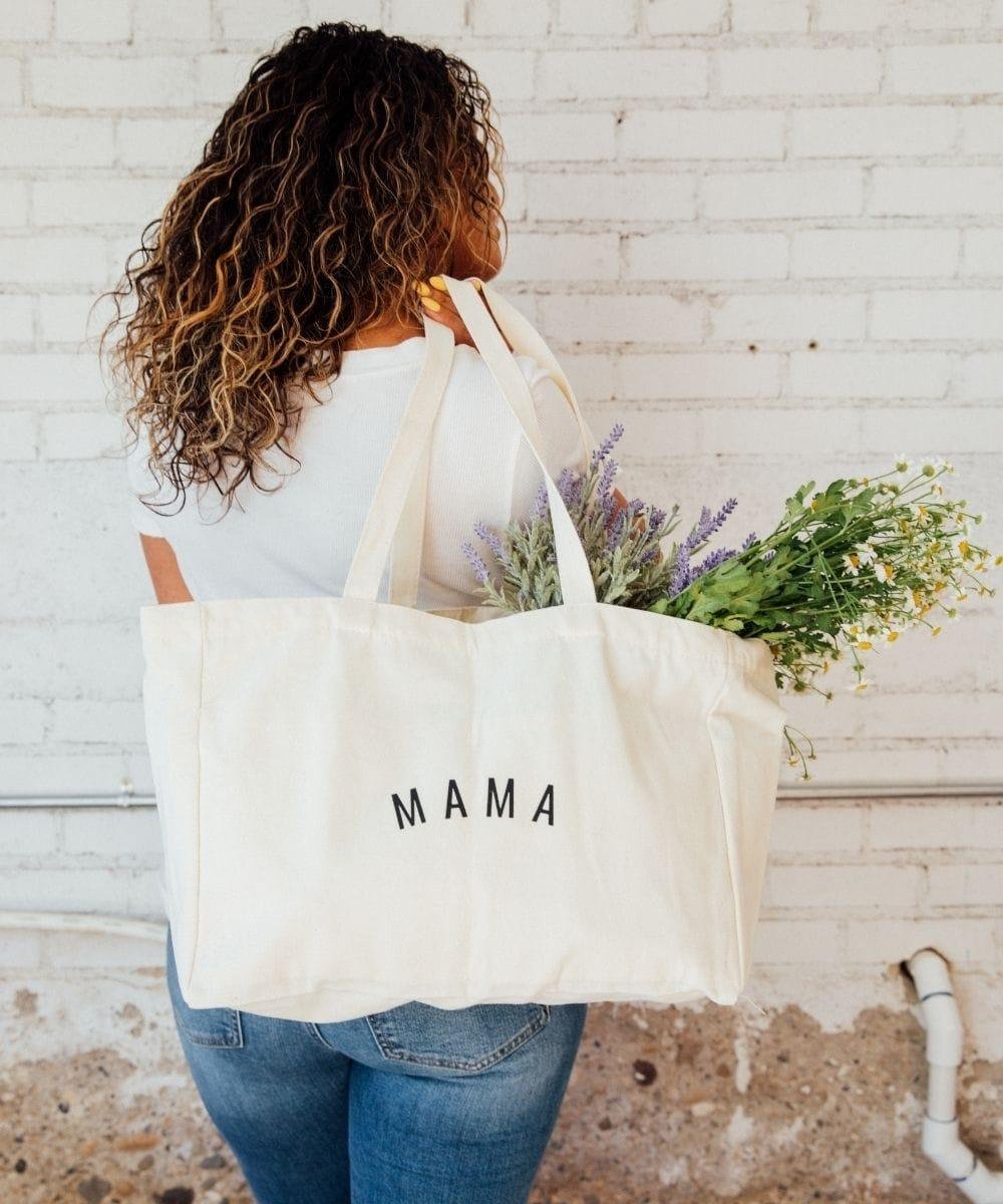 Person holding a tote bag with 'MAMA'.