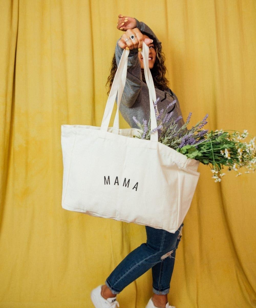 Person holding a tote bag with 'MAMA'.