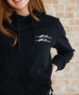 Person wearing a black hoodie with 'mama' text.