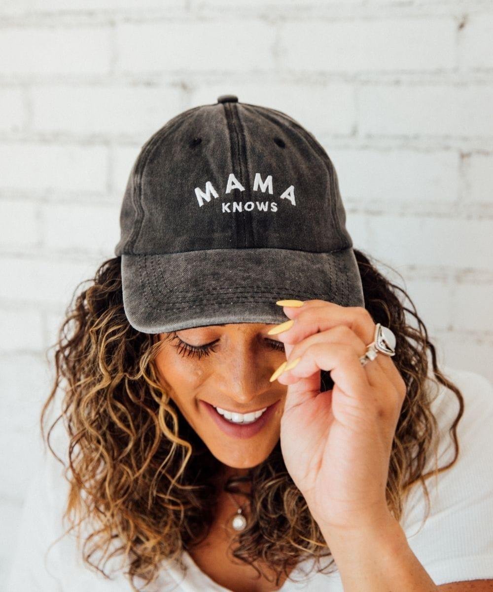Woman wearing a black cap with 'MAMA KNOWS' text.