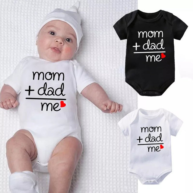 Baby wearing a white onesie with 'mom + dad me' text