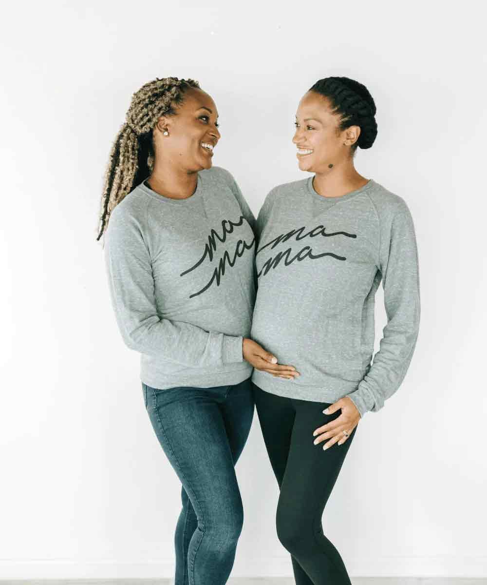 Two women wearing matching gray sweatshirts with 'Mama' printed on them.