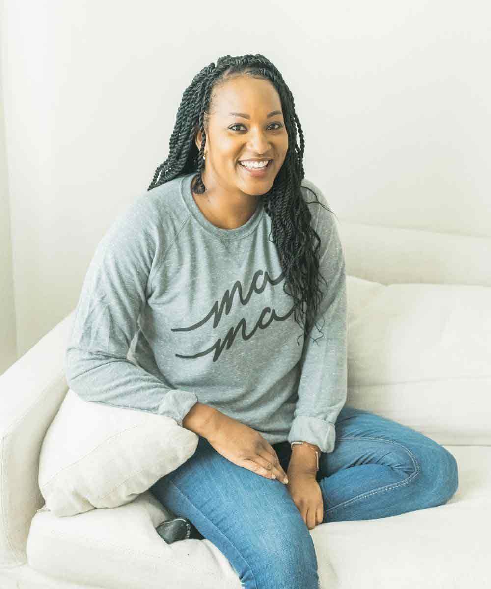 A woman wearing a gray sweatshirt with 'ma ma' text, sitting.