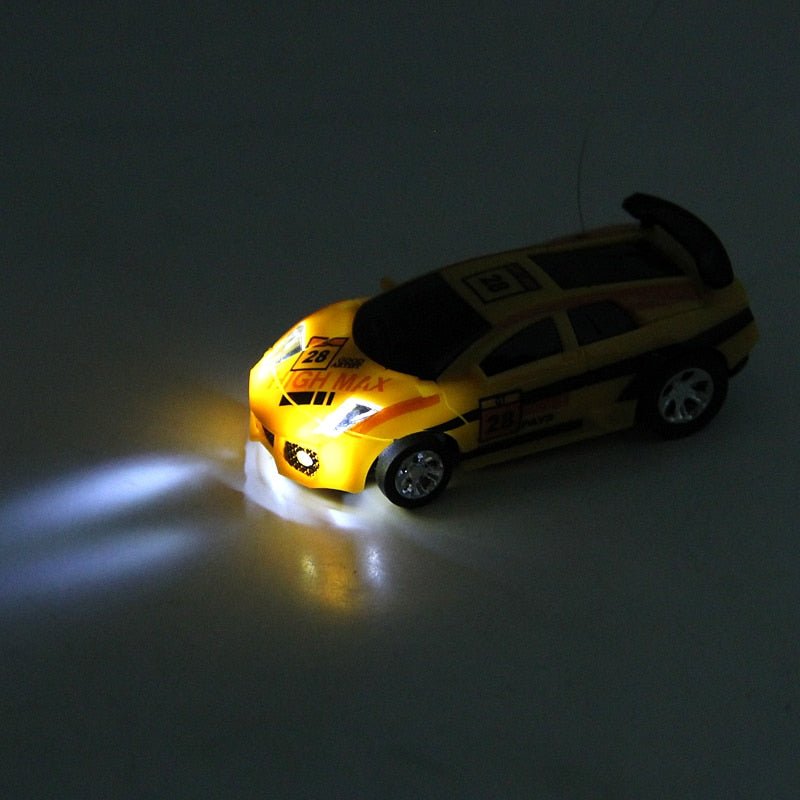 Mini RC Coke Can car with glowing LED headlights for night-time indoor racing and low-light play sessions.