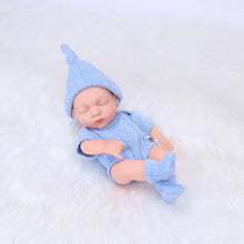 A newborn baby in a blue outfit and hat is lying.