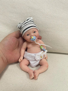 Mini reborn silicone baby doll Noah with pacifier held in hand for calming anti-stress play and lifelike doll display.