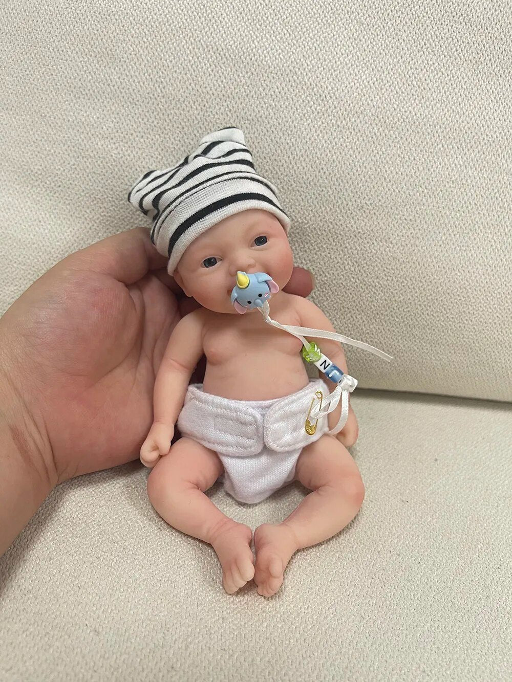 Mini reborn silicone baby doll Noah with pacifier held in hand for calming anti-stress play and lifelike doll display.
