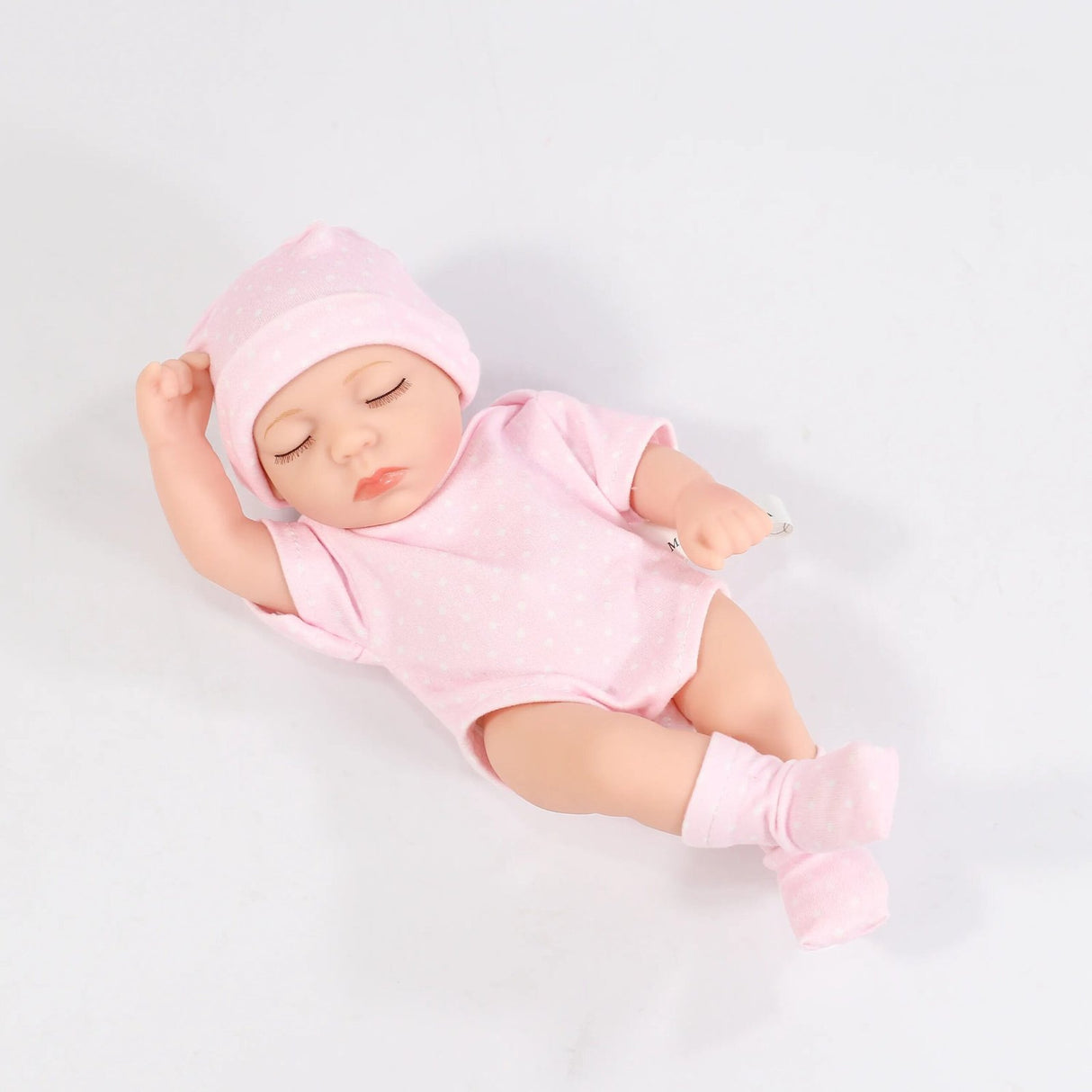 Baby doll in pink outfit and hat on a light gray background