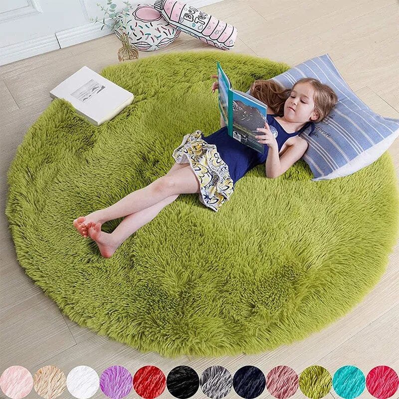 Child reading a book on a green round rug in a room.