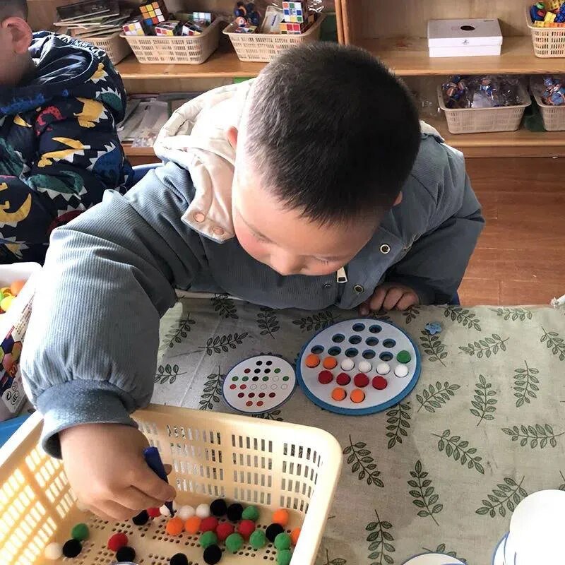 Child playing with colorful pom-poms 