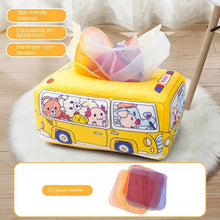 Yellow cartoon bus-shaped Montessori Magic Tissue Box with tissues shown on a wooden floor for baby play.