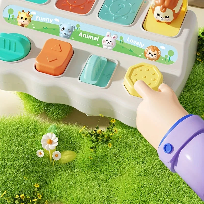 Child's finger pressing a yellow button on the pop-up animal toy on a grass background