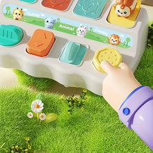 Child's finger pressing a yellow button on the pop-up animal toy on a grass background