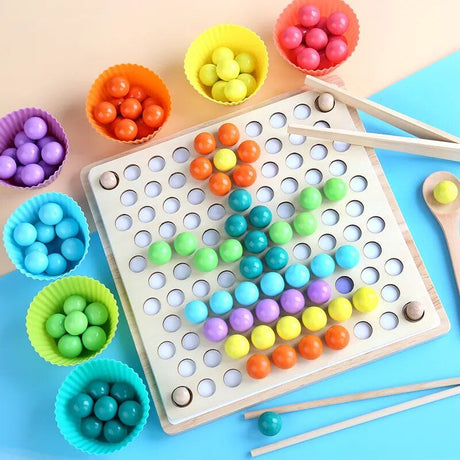 Colorful game board with wooden sticks and small bowls of multicolored beads