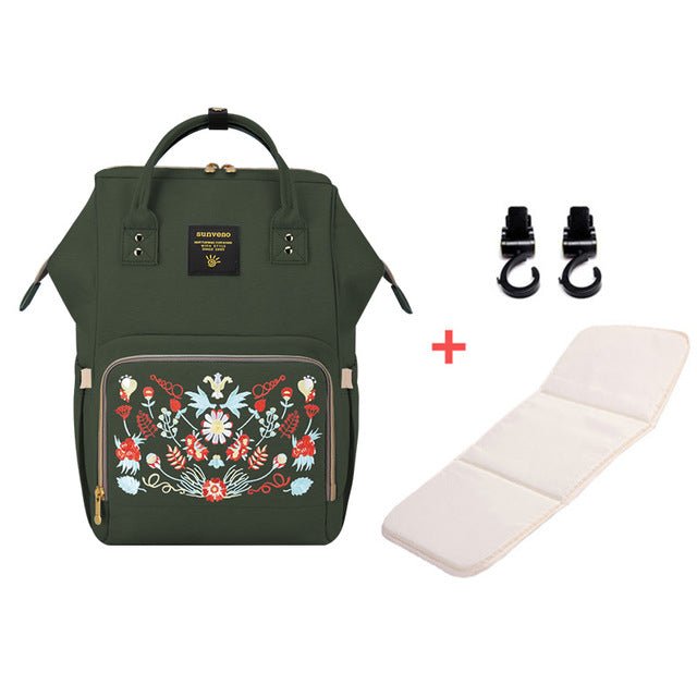 Green backpack with floral embroidery, white mat, and black hooks