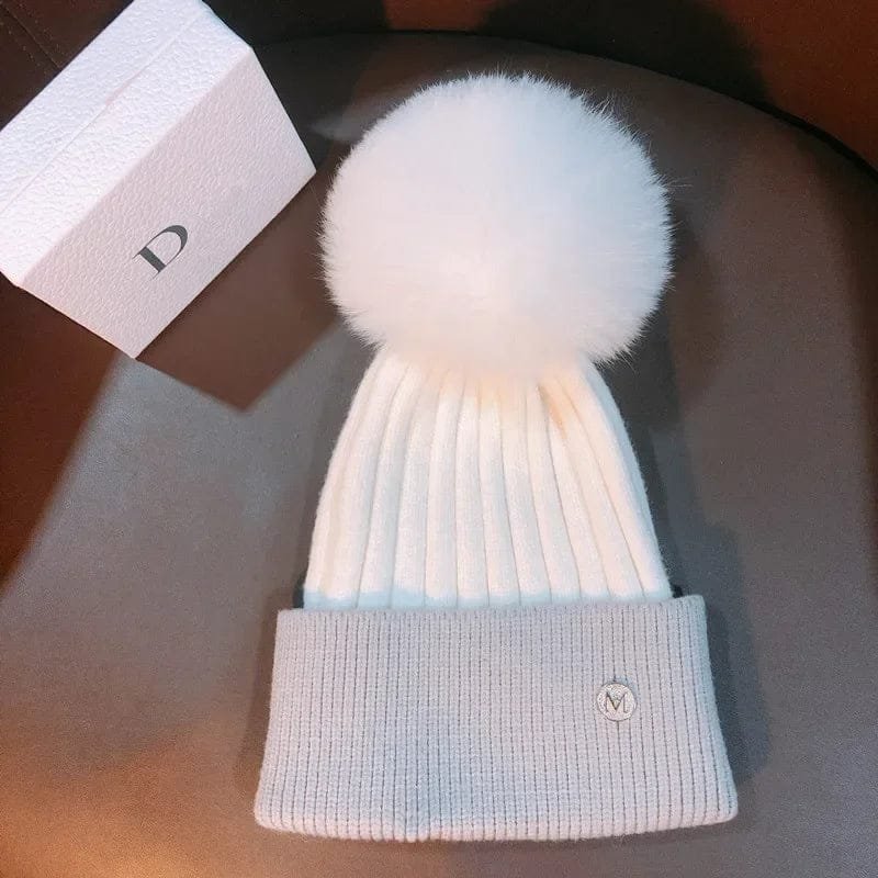 Natural mink pom pom wool beanie knitted hat flat lay for children's winter dressing and ear protection.