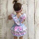 Child wearing a colorful dress with ruffles and bows.