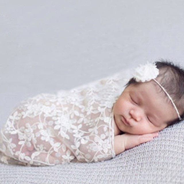 Newborn white lace swaddle wrap and headband in a studio photo for maternity and newborn portrait sessions.