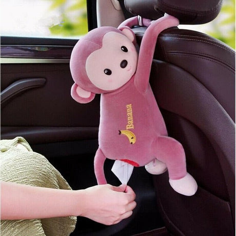 Pink monkey plush toy with a banana on a car seat