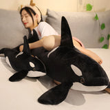 Person lying on a couch with two large plush orca whales.