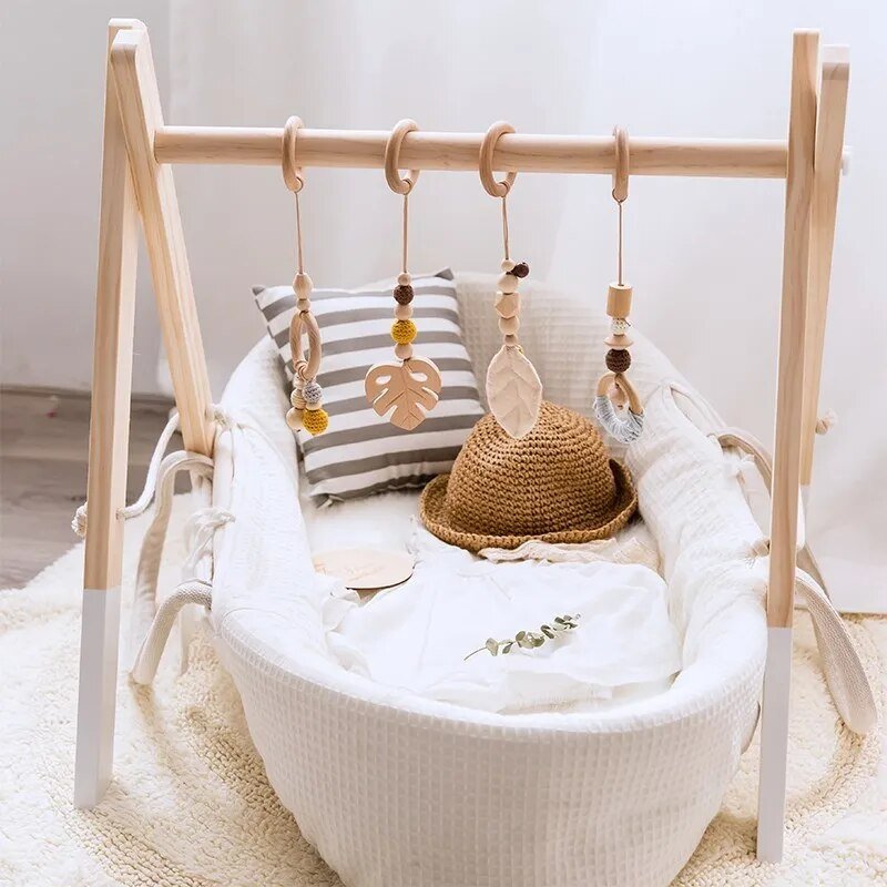 Wooden play gym with sensory mobile arranged over a crib mattress for calm visual play before naps.