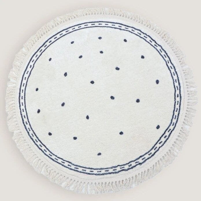 Round white cloth with blue polka dots and trim on a light gray background