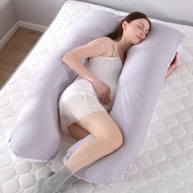 Oversized U shaped pregnancy pillow wrapping the body for cocooned rest and steady sleeping positions.