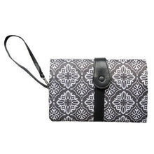 Waterproof diaper changing mat with urine pad layer folded as a patterned clutch with strap.