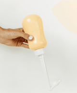 Hand holding a beige bottle with a white cap.