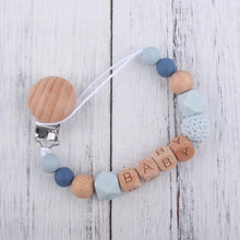 Personalised soother clip chain with a baby name, keeping dummies within reach during car rides and cot naps.