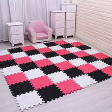 Pink, black, and white EVA foam puzzle mat laid over a wood floor for comfortable toddler play.