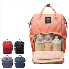 Pink diaper bag set styled with bottles, a towel, and matching pouches for organized baby travel.